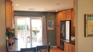 Una cocina moderna con armarios de madera, un refrigerador de acero inoxidable y un comedor con mesa y sillas.