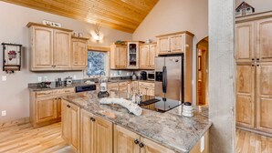 A kitchen with wooden cabinets, granite countertops, and a stainless steel refrigerator.