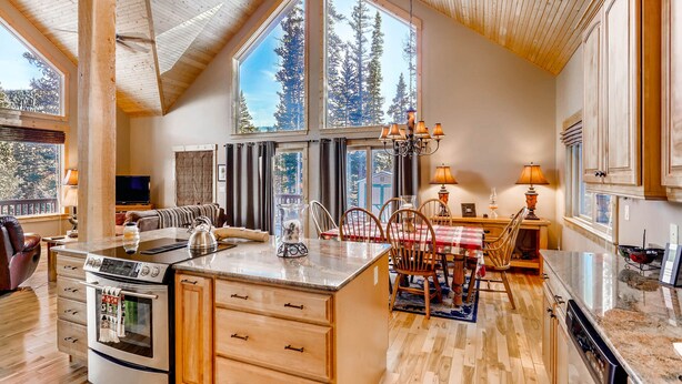 A spacious kitchen with a large island, wooden cabinets, and a dining area with a table and chairs.