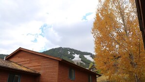 Un edificio de madera con techo inclinado, pared de ladrillo y vista a una colina nevada.