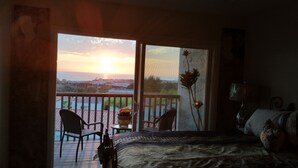Ein Schlafzimmer mit Balkon und Blick auf einen Sonnenuntergang.