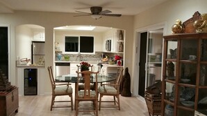 Eine moderne Küche mit Essbereich, ausgestattet mit einem Glastisch, Holzstühlen und einem Deckenventilator.