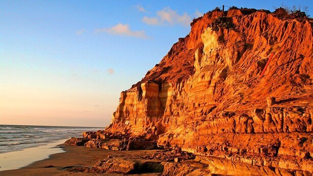 Eine Küstenklippe mit Sandstrand und Meerblick.