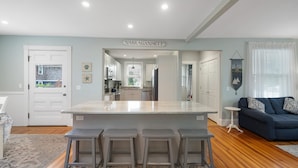 Une cuisine moderne dotée d’un îlot central, de tabourets de bar et donnant sur la salle à manger.