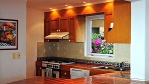 Een keuken met houten kastjes, een fornuis en een raam met bloemen.