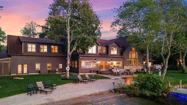 Ein zweistöckiges Haus mit Terrasse und einem kleinen Teich.
