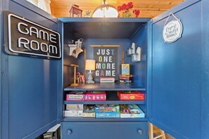 A blue cabinet with a 'GAME ROOM' sign, a motivational quote, and various board games.