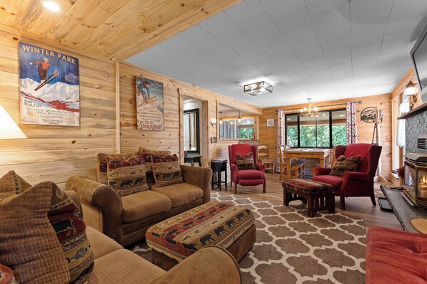 A cozy cabin interior with wooden walls, a fireplace, and a large window.