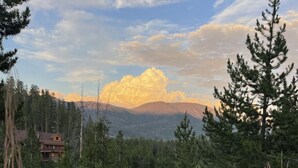 Una baita circondata da una fitta foresta e montagne.
