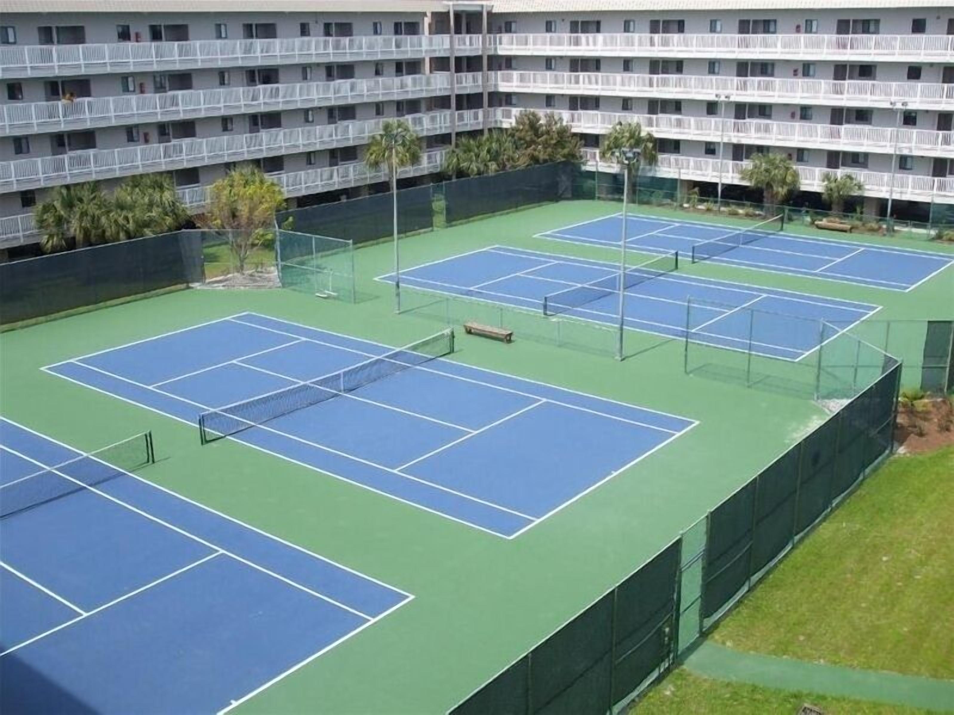Een hotel met meerdere verdiepingen en een tenniscomplex.