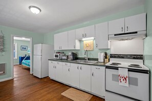 Fully equipped kitchen with a stainless steel stove, microwave, coffee maker, and sink.