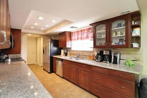 Una cocina moderna con encimeras de granito, armarios de madera y electrodomésticos integrados.