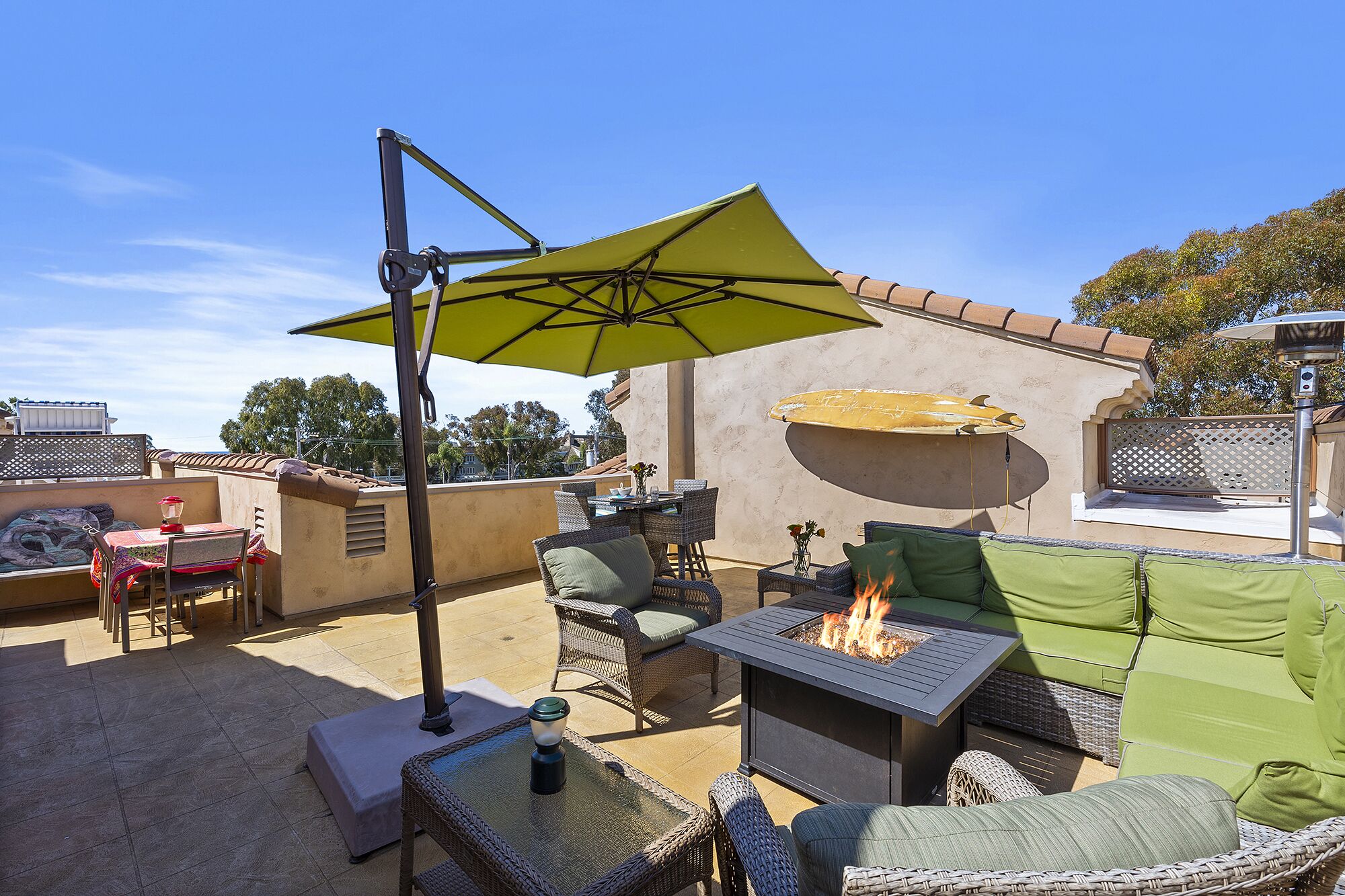 Un patio al aire libre con una chimenea, muebles de mimbre y un paraguas grande.