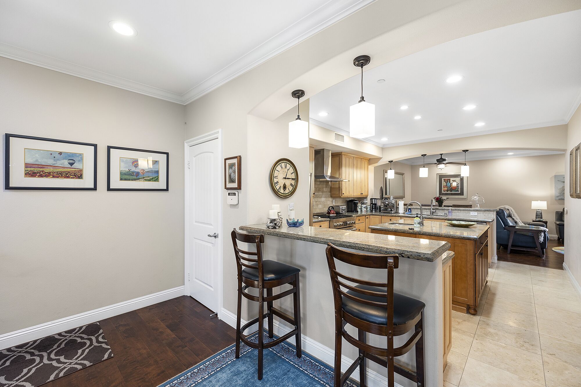 A modern kitchen with a central island, bar stools, and pendant lighting.
