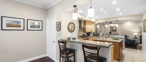 A modern kitchen with a central island, bar stools, and pendant lighting.