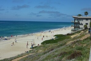 A beach with a volleyball net, people, and a building with balconies. - Elegant Village beach house. Private rooftop deck. Walk to beaches and shops. AC (Carlsbad)