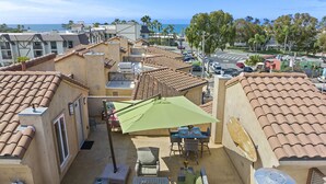 A rooftop patio with outdoor furniture, a green umbrella, and a satellite dish. - Spacious Village beach house. Private rooftop deck. Walk to beaches and shops.  (Carlsbad)