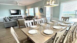 A dining area with a large table set for six, surrounded by wooden chairs. - OCEAN FRONT with POOL, Great LOCATION near pier, 5 bed & 5 bath (Ocean Isle Beach)