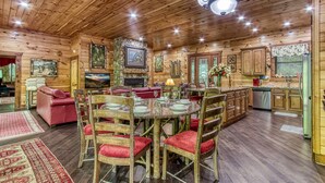 A wooden cabin interior with a dining area, kitchen, and living room. - RIVERFRONT LUXURY LODGE/4 KING SUITES/Swim Spa/Game Room/Fire Pit/4,200 Sq. Ft. (Sevierville)