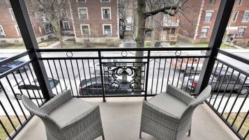 Een balkon met twee rieten stoelen en een metalen hekwerk.