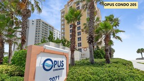 Une enseigne indiquant « Opus Condominium 205 », avec un immeuble moderne en arrière-plan.