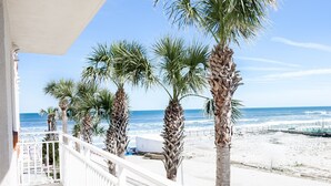 Un balcon avec vue sur la plage, les palmiers et l’océan.
