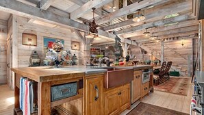 A rustic kitchen with wooden cabinets, a large island, and a hanging light fixture. - LUXURY 4 Kng Bdrm, 4.5 Bth, Gourmet Kitchen, Pavilion; TV, Fire Place, Heaters (Asheville)