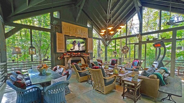 A spacious outdoor lounge with wicker furniture, a fireplace, and large windows offering a view of the surrounding greenery. - LUXURY 4 Kng Bdrm, 4.5 Bth, Gourmet Kitchen, Pavilion; TV, Fire Place, Heaters (Asheville)