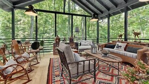 A spacious outdoor seating area with wooden furniture, a patterned rug, and a view of the forest. - LUXURY 4 Kng Bdrm, 4.5 Bth, Gourmet Kitchen, Pavilion; TV, Fire Place, Heaters (Asheville)