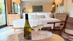 Une chambre à coucher avec un lit, une table de chevet sur laquelle se trouvent une bouteille de vin et des verres, et une vue sur l’extérieur.