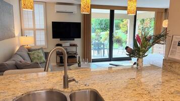 A modern kitchen with a granite countertop, stainless steel sink, and pendant lighting.