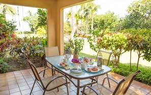 Guests can dine al fresco in this sheltered outdoor space, surrounded by lush gardens and a beautifully set table for four.
