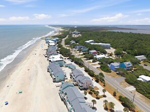 Hotel à beira-mar com quartos com vista para a praia, estrada e vegetação ao redor.