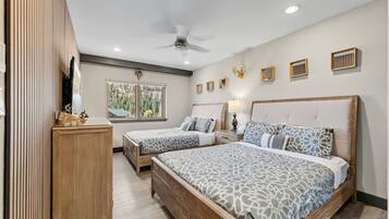 A bedroom with two beds, a ceiling fan, a window with a view, and wall-mounted decor.