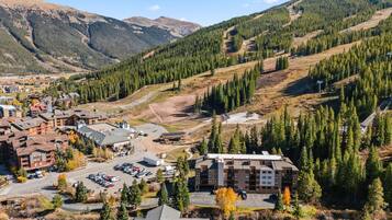 A mountain resort with multiple buildings, a parking lot, and a ski lift.