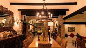 A dining area with a wooden table, wicker chairs, and a chandelier.