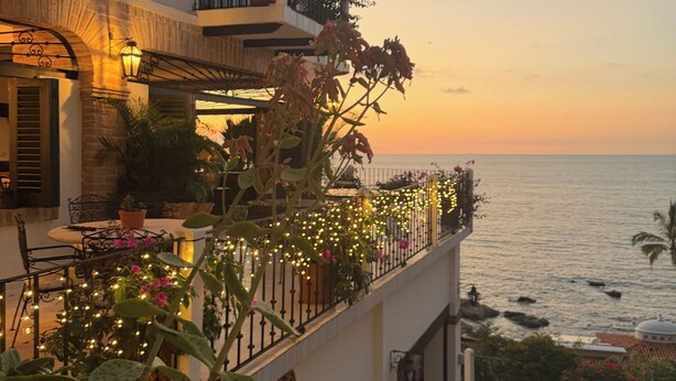 A coastal building with balconies, outdoor seating, and string lights.