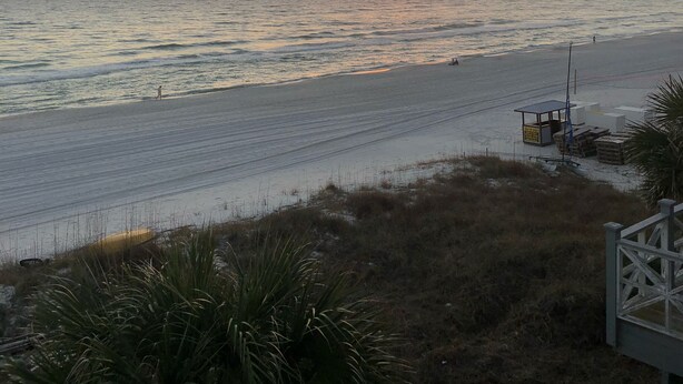 A beach with a sunset, calm sea, and a lifeguard tower.