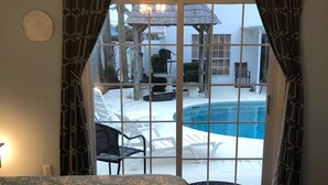 A bedroom with a view of a pool and outdoor seating.