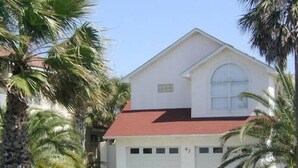 A two-story house with a red roof, a garage, and a white picket fence.