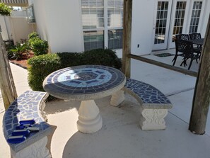 Enjoy a tranquil outdoor space with a mosaic-tiled table and bench, surrounded by lush greenery.