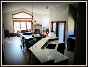 Uma sala de estar ampla com uma grande mesa de jantar, lareira e vista para o exterior.