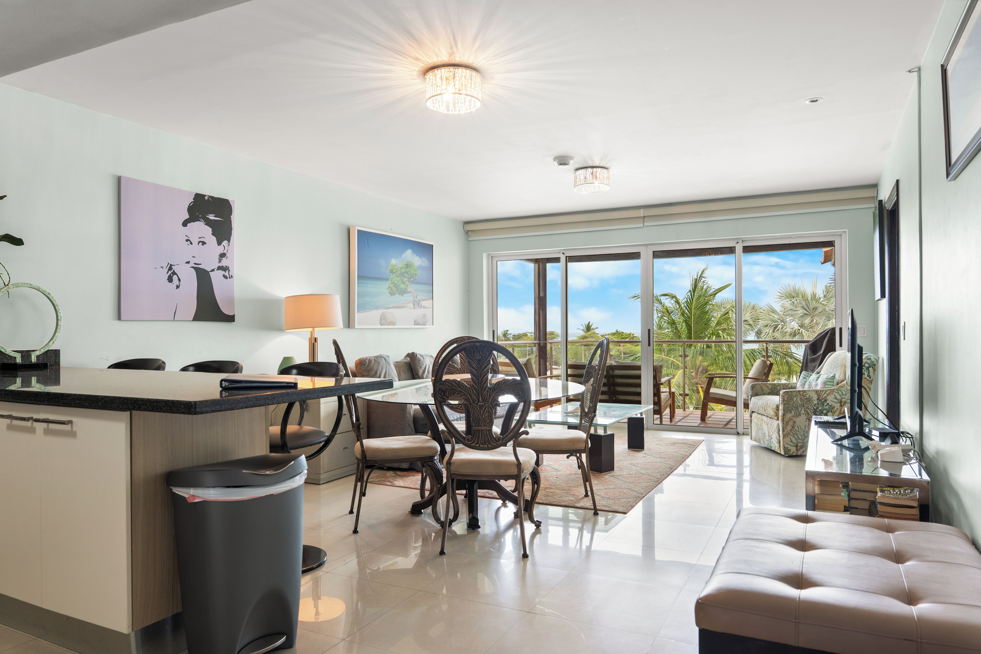 A modern kitchen with a dining area, large windows, and a view of the outdoors.