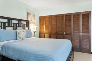 A bedroom with a bed, a nightstand, a lamp, and a wardrobe.