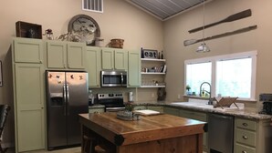 A kitchen with a central island, stainless steel appliances, and a window with a city view. - Hidden Piece of Heaven on Lake Limestone (Thornton)