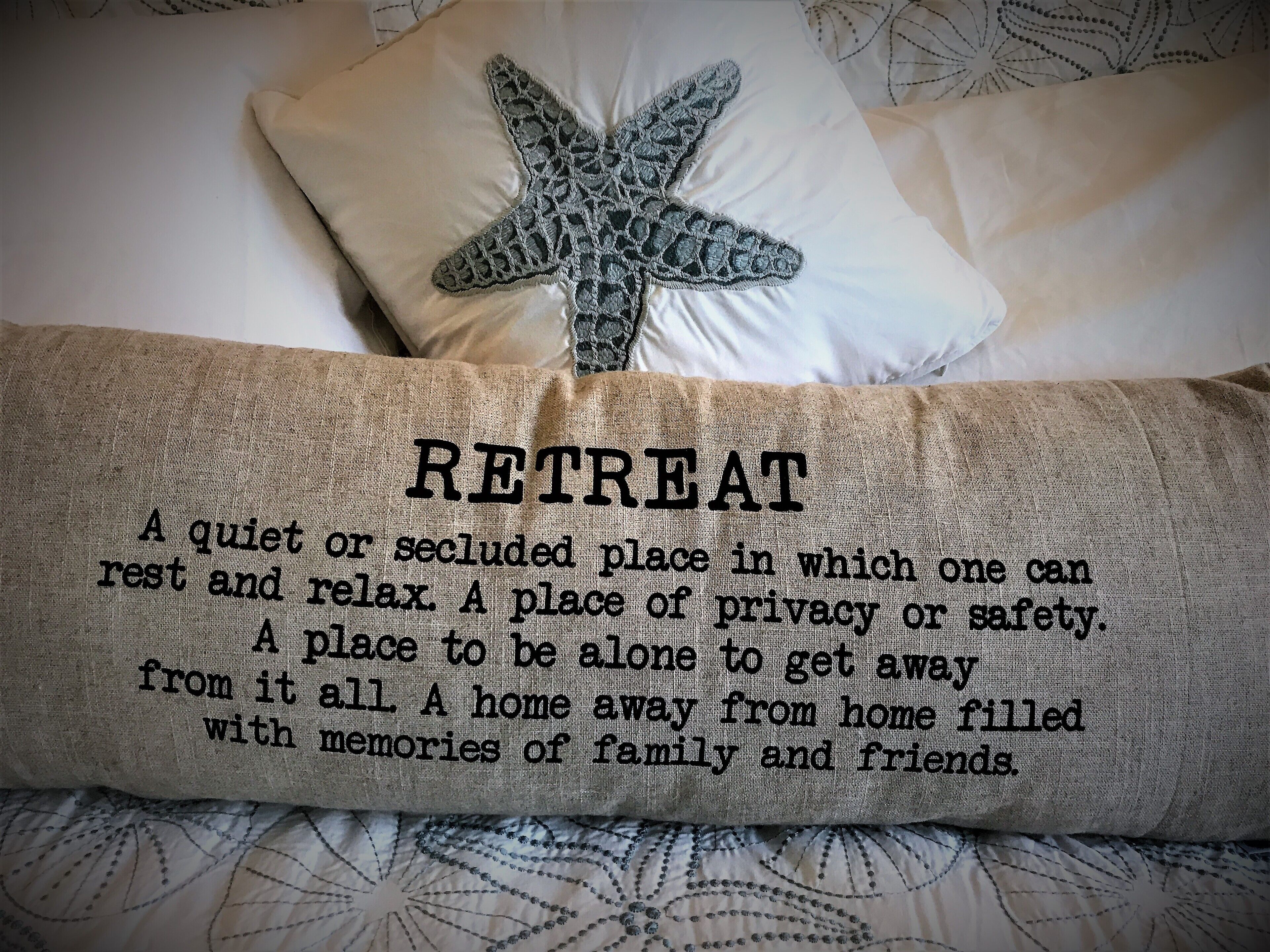 Un coussin orné d’un motif d’étoile de mer et un tissu sur lequel figure le mot « RETREAT » accompagné de sa définition.