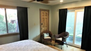 A bedroom with a large bed, two wicker chairs, a door, and a sliding glass door leading to an outdoor area. - Amazing Location in Beautiful Blue Mountain Beach.  75 Yards from the Sand...   (Santa Rosa Beach)