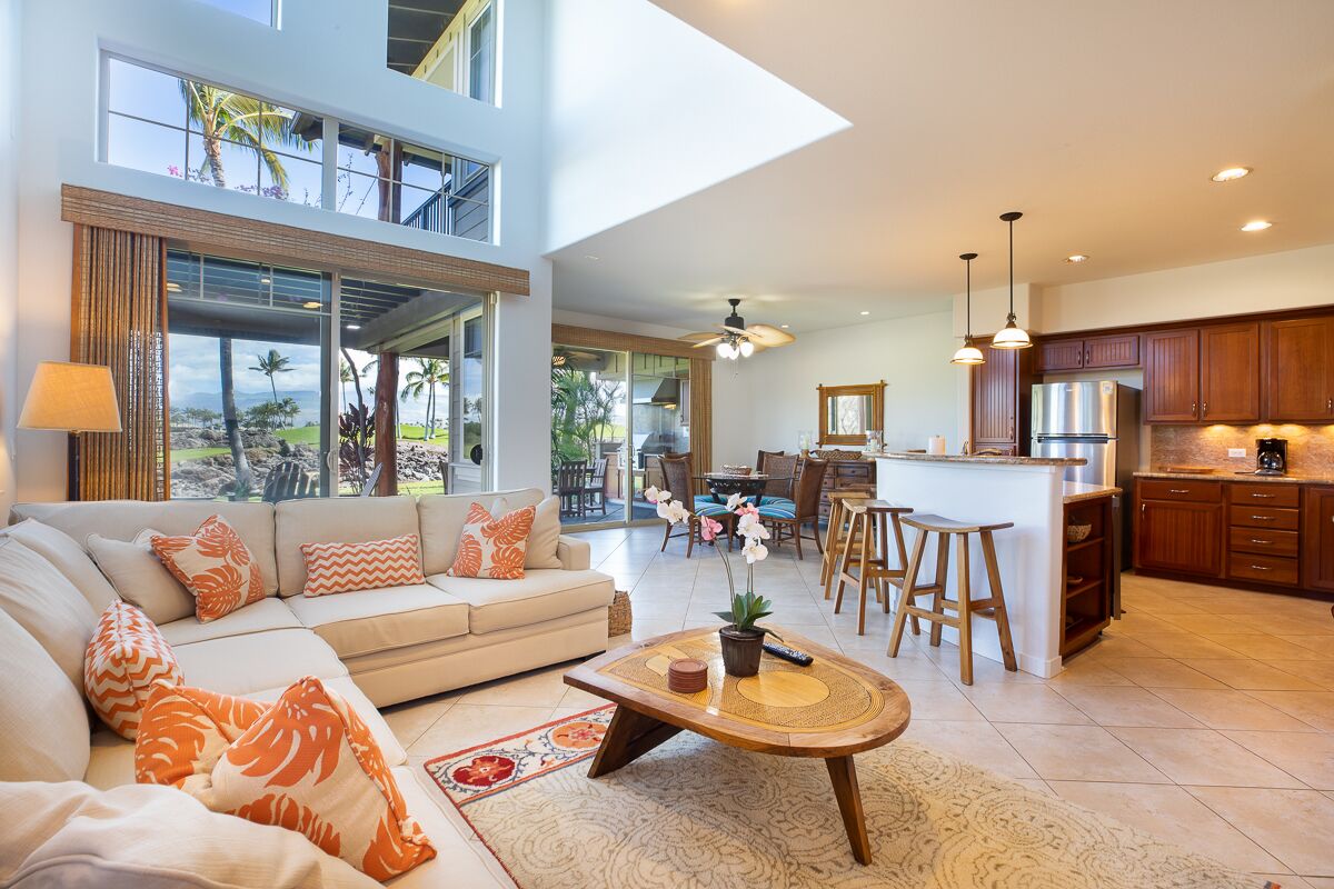 Uma sala de estar ampla com sofá, mesa de centro e vista para o exterior.