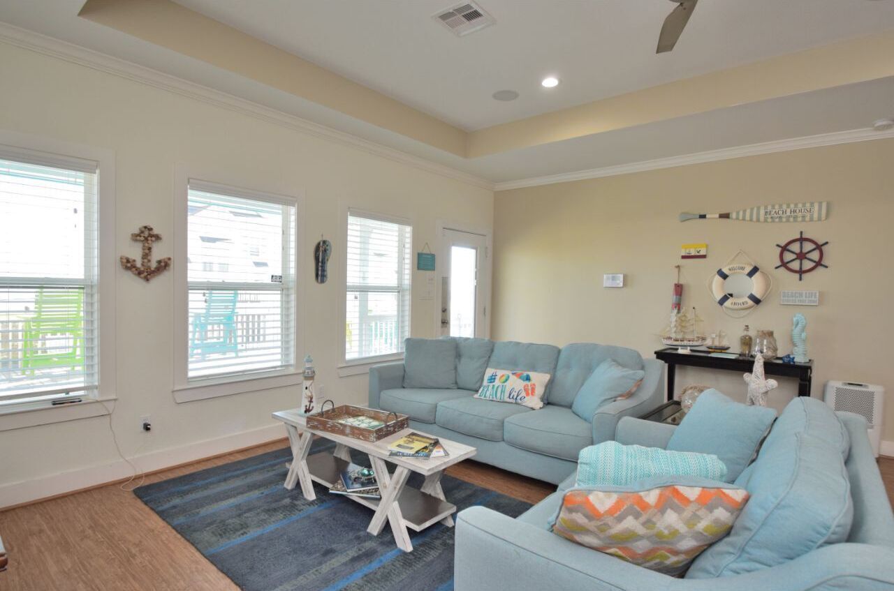 A living room with a light blue sofa, a coffee table, and nautical decor including a ship wheel and anchor.
