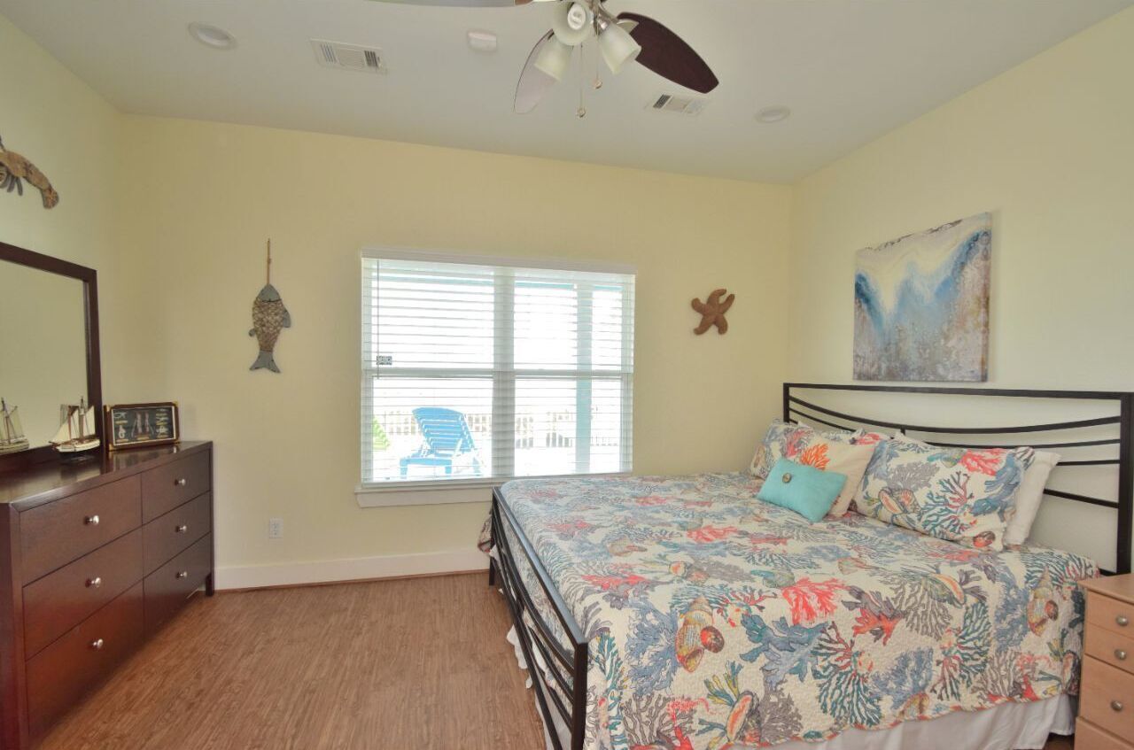 Une chambre à coucher avec un lit, une commode et un ventilateur de plafond.